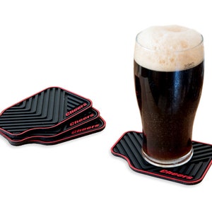 May include: Three black and red silicone coasters with the word "Cheers" printed on each. A glass of dark beer is sitting on one of the coasters.