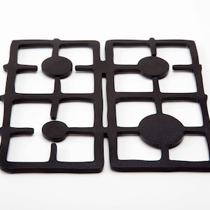 May include: Black metal kitchen trivet with a geometric design. The trivet has a grid pattern with circles in each square.