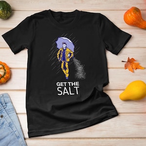May include: Black t-shirt with a graphic of a person walking in the rain with an umbrella and the text "GET THE SALT".