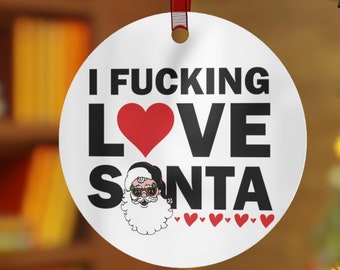 May include: White round Christmas ornament with the text "I FUCKING LOVE SANTA" in black letters with a red heart between "LOVE" and "SANTA". A cartoon image of Santa Claus wearing sunglasses is below the text.
