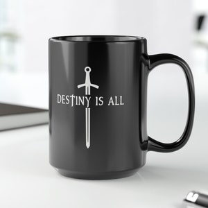 May include: Black ceramic coffee mug with a white sword graphic and the text "Destiny is All".