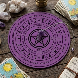 May include: A round purple dowsing board featuring a central black pentagram, the alphabet, numbers zero through nine, days of the week, and zodiac signs. A pointed amethyst crystal pendulum on a silver chain rests on the board surface.
