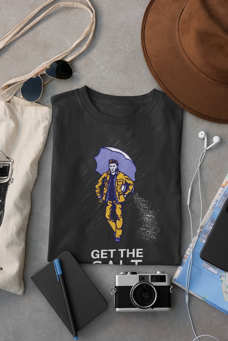 May include: Black t-shirt with a graphic of a person walking in the rain with an umbrella and holding a bag of salt. The text "GET THE SALT" is printed below the graphic.