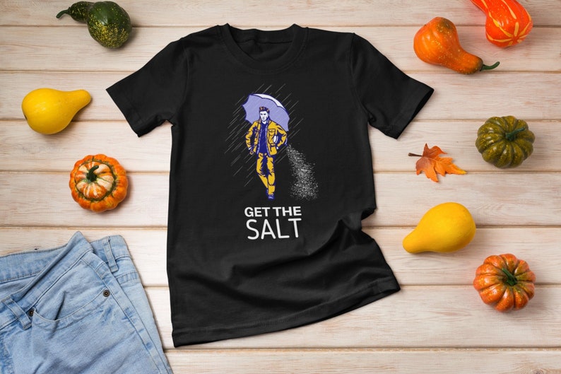 May include: Black t-shirt with a graphic of a person walking in the rain with an umbrella and the text "GET THE SALT".