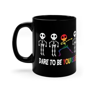 May include: Black coffee mug with a rainbow skeleton design and the text "Dare to be yourself".