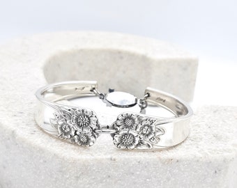 May include: Silver bracelet made from a vintage spoon with a floral design and a chain link closure.