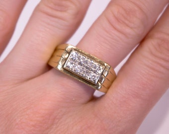 May include: A gold band ring with a rectangular-shaped setting featuring a row of small diamonds.