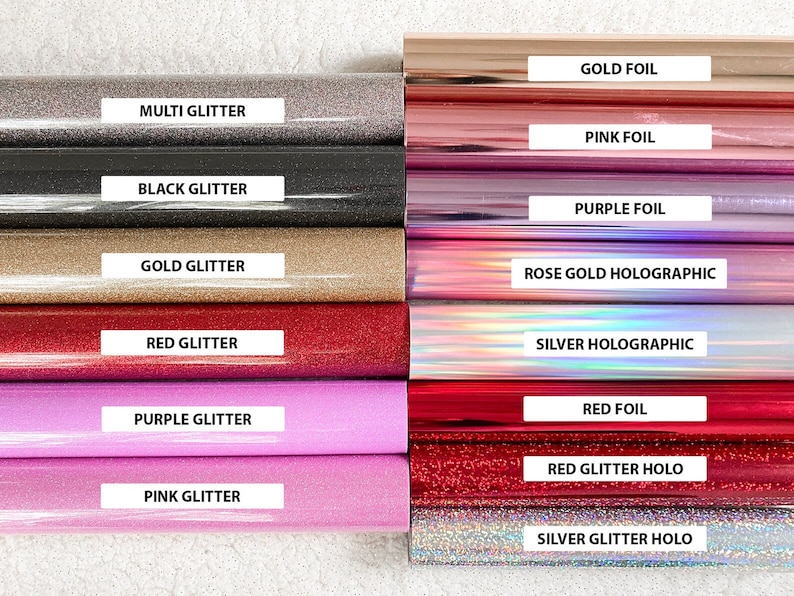 K&ouml;nnte beinhalten: Eine Sammlung von 12 verschiedenen farbigenen Vinylfolien mit Glitzer- und Hologramm-Oberfl&auml;chen. Die Folien sind mit ihren Namen beschriftet: Goldfolie, Multi-Glitter, Rosafolie, Schwarz-Glitter, Lilafolie, Gold-Glitter, Ros&eacute;gold-Hologramm, Rot-Glitter, Lila-Glitter, Silber-Hologramm, Rotfolie, Rot-Glitter-Holo, Rosa-Glitter und Silber-Glitter-Holo.