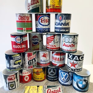 May include: A collection of vintage-style mugs featuring various automotive and oil company logos, including Castrol, Esso, Shell, Texaco, Pepsi, Honda, Audi, Yamaha, and Volkswagen. The mugs are white with a distressed, vintage look and feature black dripping paint.