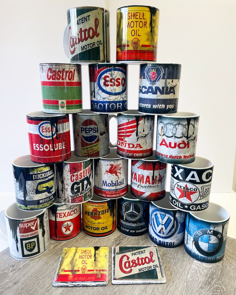 May include: A collection of vintage-style mugs featuring various automotive and oil company logos, including Castrol, Esso, Shell, Texaco, Pepsi, Honda, Audi, Yamaha, and Volkswagen. The mugs are white with a distressed, vintage look and feature black dripping paint.