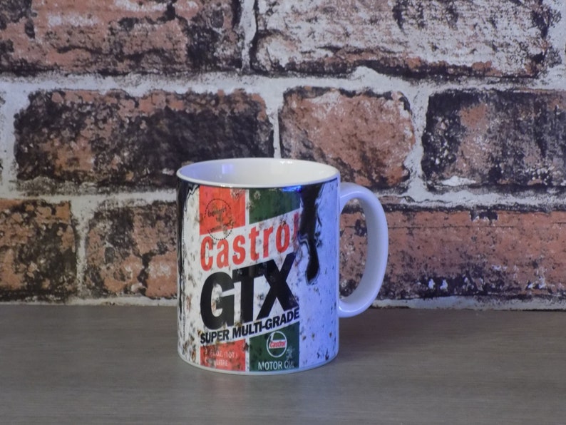 May include: White ceramic mug with a vintage Castrol GTX Super Multi-Grade motor oil can design. The design features a red, green, and black color scheme with a distressed look.