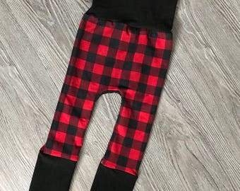Op de afbeelding: Rode en zwarte geruite leggings met zwarte omslagmanchetten. De leggings hebben een hoge taille en zijn gemaakt van een zachte, rekbare stof.