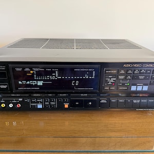 May include: A black and silver Sony Audio/Video Control Center receiver. The receiver has a digital display, numerous buttons, and input jacks. The top has a vented design. The text "SONY" is visible on the left side.