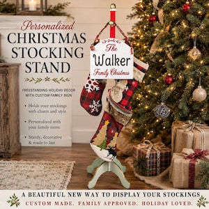 May include: A metal Christmas stocking stand with a white wooden sign reading The Walker Family Christmas. The stand features a red ribbon hanger and holds two fabric stockings, one with a red plaid pattern and one with a moose and tree design.