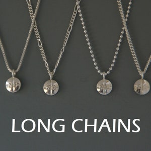 Può includere: Quattro catene d'argento con un ciondolo a forma di pillola che dice "20" su ciascuna. Le catene sono appese su uno sfondo grigio. Il testo "LONG CHAINS" è nella parte inferiore dell'immagine.