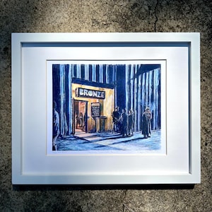 Pode incluir: Uma impressão de arte emoldurada que retrata uma cena noturna em frente a um bar chamado "BRONZE". A obra apresenta figuras em frente à entrada, com um brilho quente vindo de dentro. A impressão está em uma moldura branca.