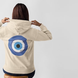 May include: A cream colored hoodie with a blue evil eye design on the back.