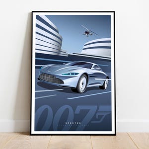 Peut inclure: Une voiture de sport Aston Martin DB10 argentée avec le texte "007 SPECTRE" et le logo de James Bond. La voiture roule sur une route avec un hélicoptère volant au-dessus.