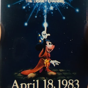 May include: A vintage Disney Channel pin featuring Mickey Mouse as a magician with a wand, a blue background with stars, and the text "The Disney Channel" and "April 18, 1983".