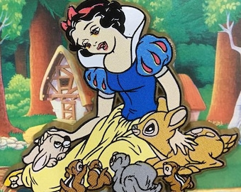 May include: Snow White, a Disney princess, is sitting with a yellow dress and blue bodice. She has a red bow in her hair and is surrounded by woodland creatures, including a fawn, a squirrel, and a rabbit. The background is a cartoon forest scene.