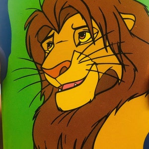 Könnte beinhalten: Eine Cartoon-Illustration eines Löwen mit braunem Fell und gelbem Gesicht. Der Löwe hat einen grünen Hintergrund hinter sich.