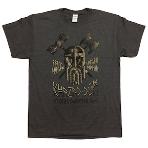 Peut inclure: Un t-shirt gris foncé avec un motif doré représentant un guerrier nain avec des haches et le texte "Khazad-dûm Strong Dwarven Folk".