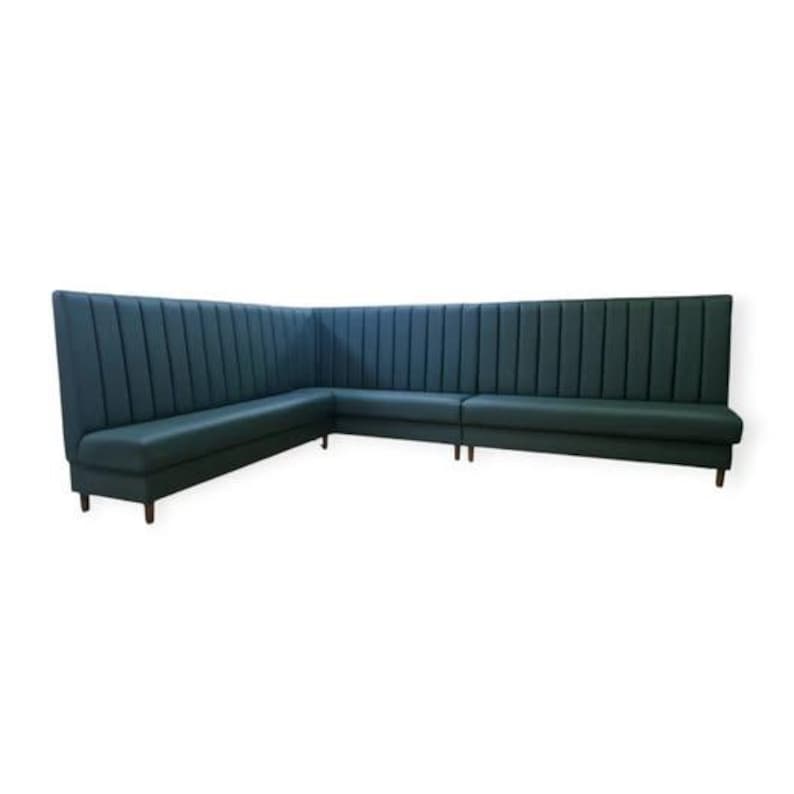 May include: A dark green L-shaped booth seating with vertical channel tufting and wooden legs.