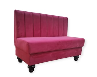 May include: A pink velvet tufted bench with a high back and four dark wood legs.