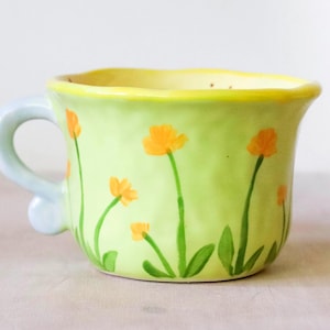 Taza Hobbit con Asa Grande en Forma de Pergamino - Millie's Pottery Flores Verdes y Naranjas con Asa Grande en Forma de Pergamino con la Casa Hobbit Asa Grande en Forma de Pergamino