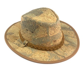 May include: A wide-brimmed cork hat with a brown leather band and braided trim. The hat has a mottled pattern of light and dark brown.