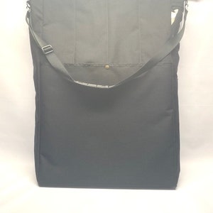 May include: A black canvas tote bag with a single strap and a gold button closure.