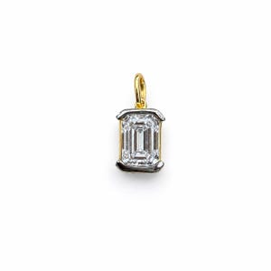May include: A rectangular emerald-cut clear gemstone pendant set in a two-tone metal frame. The center stone is held by a silver-colored bezel setting, while the top bail for attachment is crafted from polished yellow gold-colored metal.