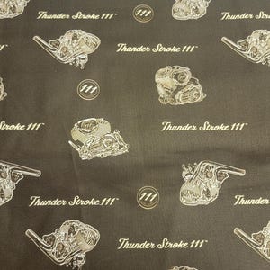 May include: A brown fabric with a repeating pattern of a motorcycle engine design and the text "Thunder Stroke 111".