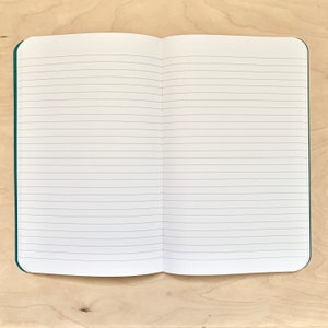 K&ouml;nnte beinhalten: Ein ge&ouml;ffnetes Notizbuch mit linierten Seiten und einem t&uuml;rkisfarbenen Einband.