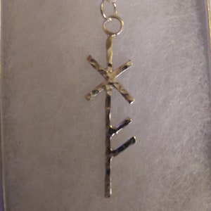 May include: Silver pendant necklace with a hammered metal design featuring a rune symbol.