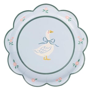 May include: A light blue paper plate with a scalloped edge. The plate features a central illustration of a white goose wearing a blue bow. Pink floral accents and a green border complete the design. The plate is designed for a party or special occasion.