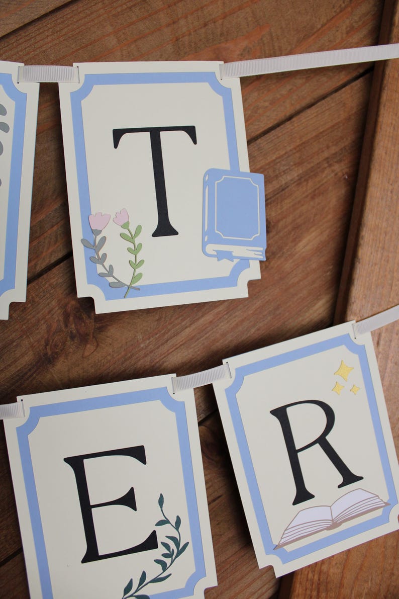 May include: A banner with individual lettered cards spelling out "TER". Each card has a light blue border and a white background. The letters are black. Some cards have floral and book illustrations.