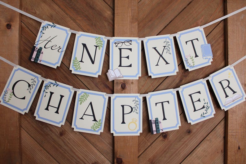 May include: A banner with the words "Her Next Chapter" in black letters on cream-colored cards with a light blue border. The banner includes illustrations of books, glasses, and a ring, strung on a white ribbon.