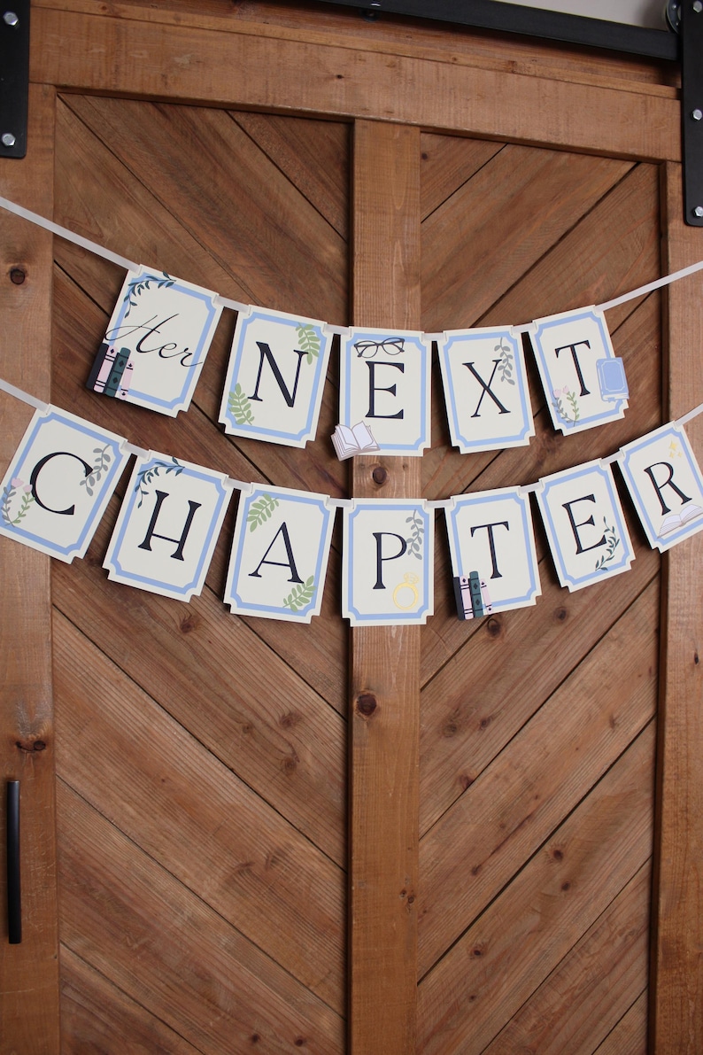 May include: A banner with the words "Her Next Chapter" in black letters on light blue and white rectangular cards. The banner is decorated with small illustrations of books, glasses, and floral accents. The banner is hanging against a wooden door.