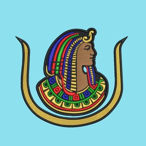 May include: An embroidered design featuring a profile of an Egyptian figure with a colorful headdress and collar, set against a light blue background. The figure is framed by a gold-colored, U-shaped element.