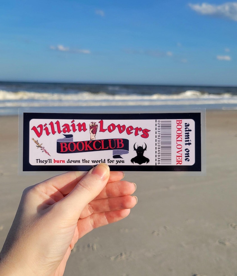 May include: A black and white ticket with red text that reads "Villain Lovers Bookclub" and "They'll burn down the world for you". The ticket also has a barcode and the text "admit one BOOKLOVER" on the right side.