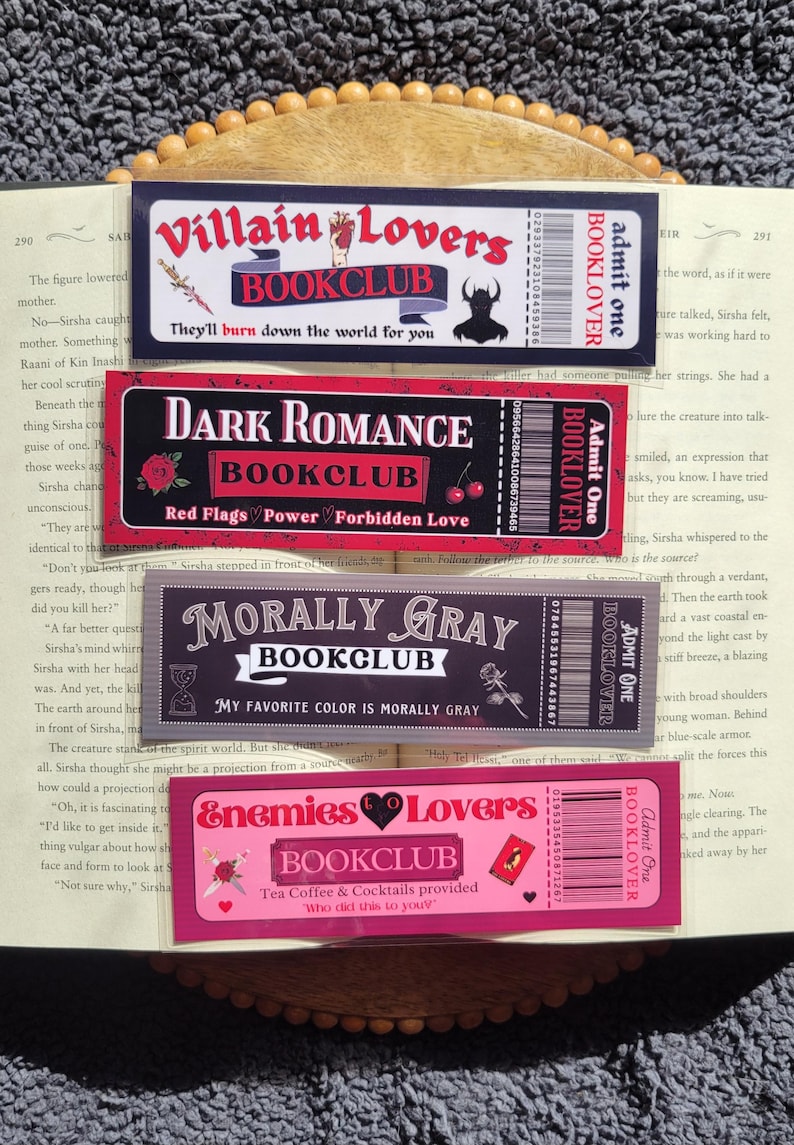 May include: Four colorful bookmarks with a book club theme. Each bookmark features a different design with a dark background and colorful accents. The bookmarks include the text "Villain Lovers Bookclub", "Dark Romance Bookclub", "Morally Gray Bookclub", and "Enemies to Lovers Bookclub".