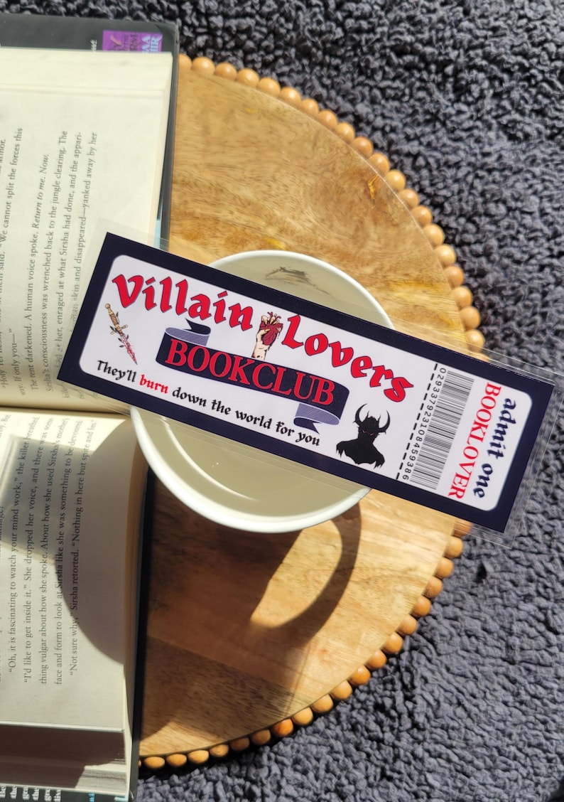 May include: A black and red bookmark with the text "Villain Lovers Bookclub" and "They'll burn down the world for you". The bookmark also has a barcode and the text "admit one BOOKLOVER".