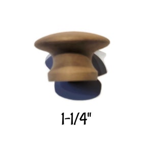 May include: A wooden cabinet knob with a mushroom-shaped design. The knob is light brown and measures 1-1/4 inches in diameter. It is a decorative hardware element for furniture and cabinetry.