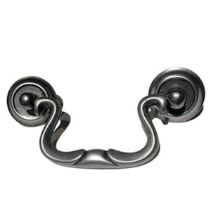 May include: Silver-toned metal drawer pull with a decorative, curved design. The pull has two round knobs on either end.