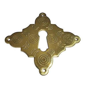 May include: A gold keyhole cover with a decorative pattern of circles and crescents.