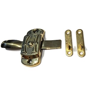 May include: A gold-toned metal latch with a decorative design. The latch has a lever handle and a hook on the other side. Two separate gold-toned metal hooks are included.