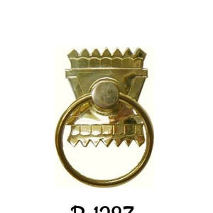 May include: Gold-toned metal ring pull with a decorative top. The top features a geometric design with a pointed top and a scalloped edge. The ring pull is labelled "B-1283".