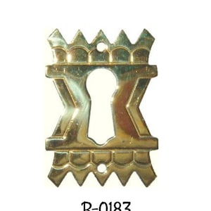 May include: A gold keyhole cover with a decorative design. The cover has a scalloped edge and a pointed top. The keyhole is in the center of the cover. The cover is labeled "B-0183".