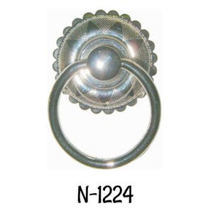 May include: Silver ring pull cabinet knob with a decorative, patterned, circular base. The base has a scalloped edge. The knob is labeled "N-1224".